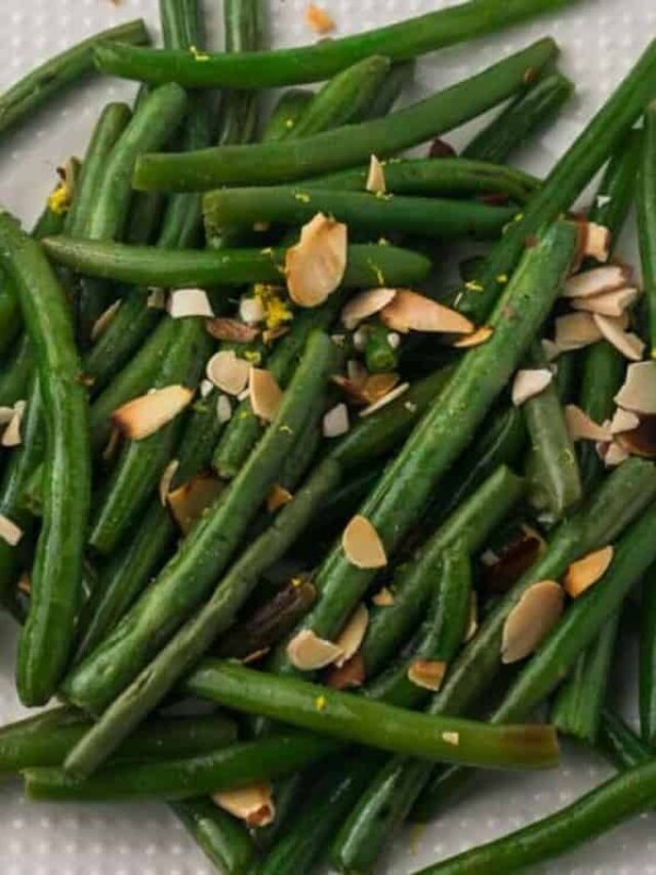 a white plate of sautéed green beans and almonds