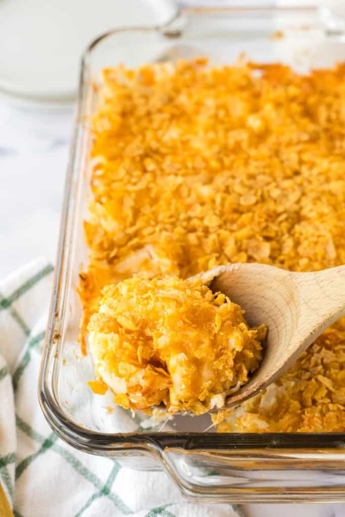Spoonful of funeral potatoes from a casserole dish.