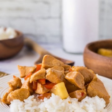 a plate of hawaiian chicken in sauce with pineapples over white rice