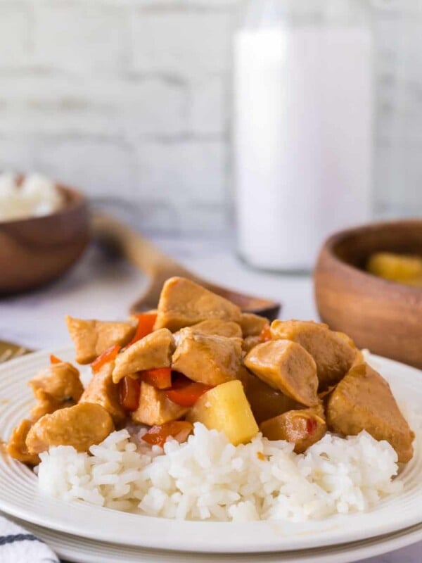 a plate of hawaiian chicken in sauce with pineapples over white rice