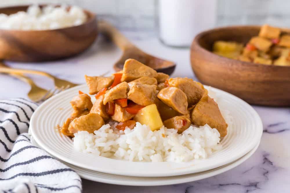 a plate of hawaiian chicken in sauce with pineapples over white rice