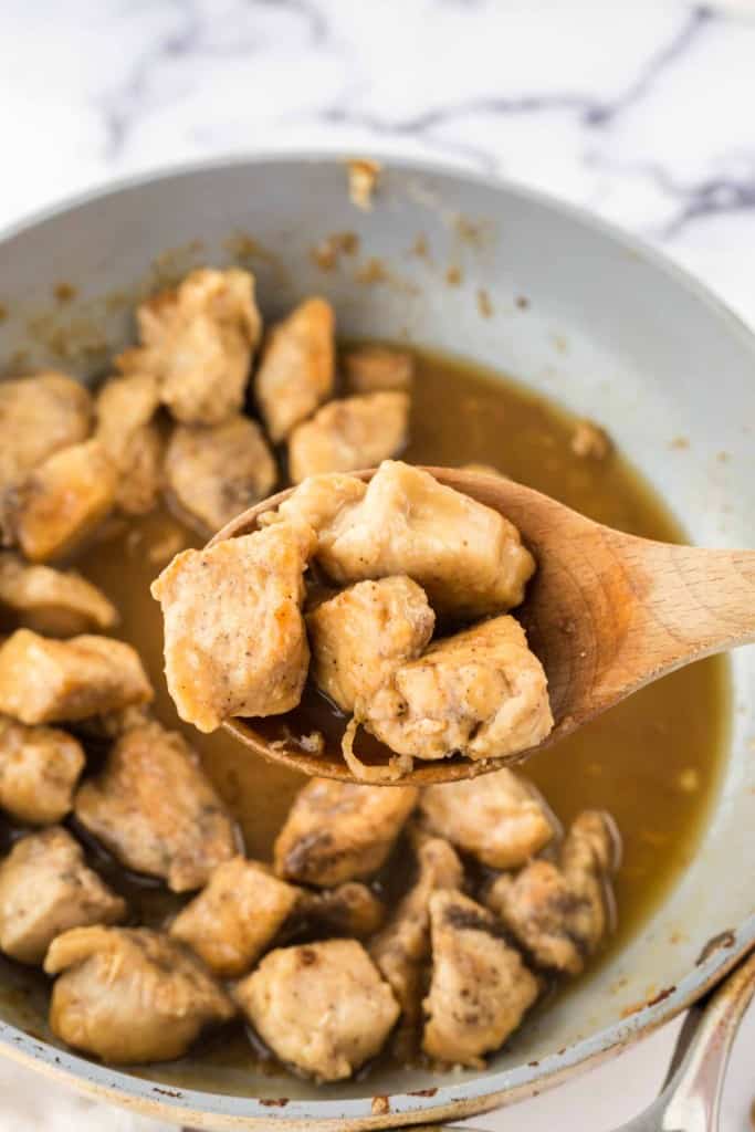 honey chicken on a wooden spoon
