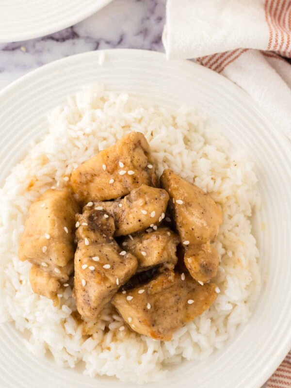 top view close up of honey chicken cubes over rice on a white plate