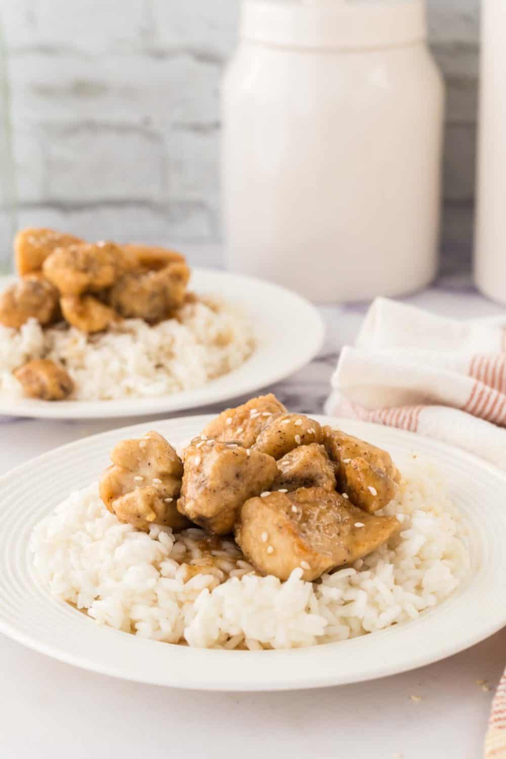 honey chicken cubes over rice on a white plate