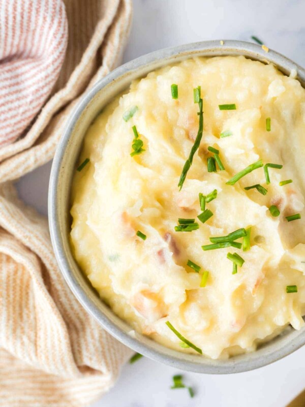 loaded mashed potatoes in a small serving bowl with golden spoons
