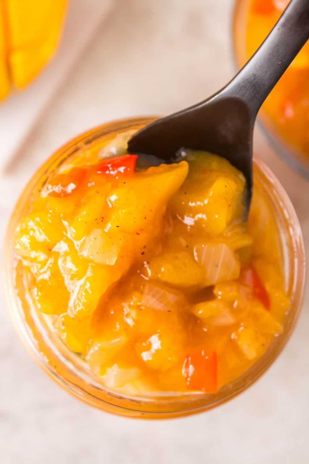 top view of mango chutney in a small mason jar on a spoon