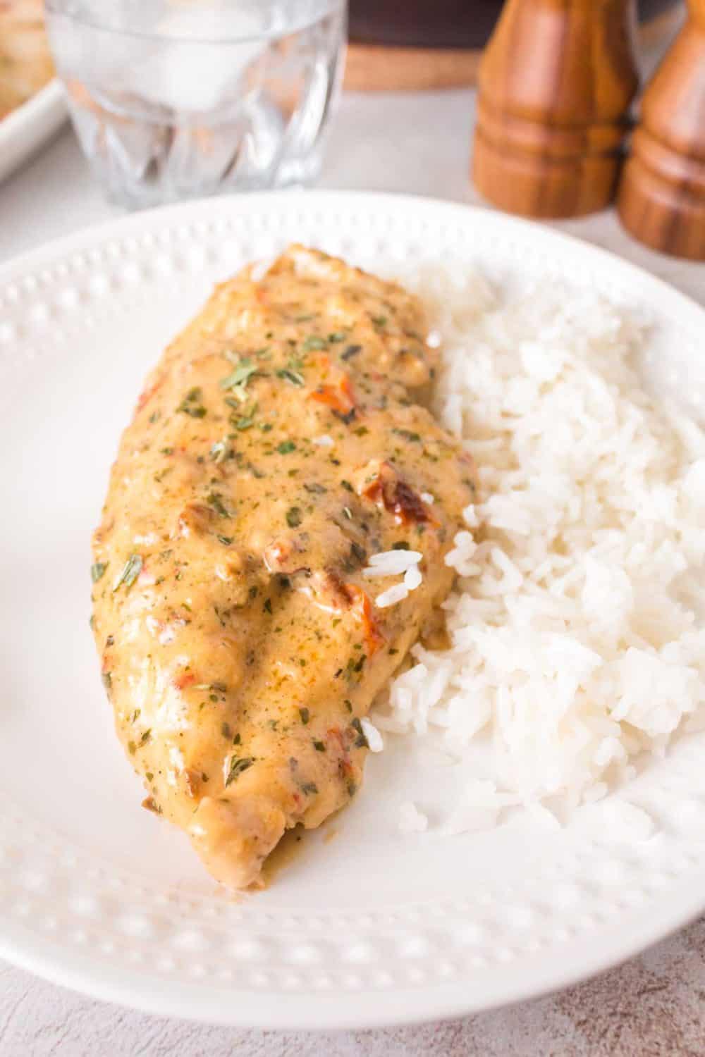 one piece of marry me chicken smothered in sauce on a white plate with rice