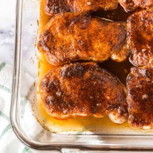 clear baking dish with seasoned pork chops in a sauce