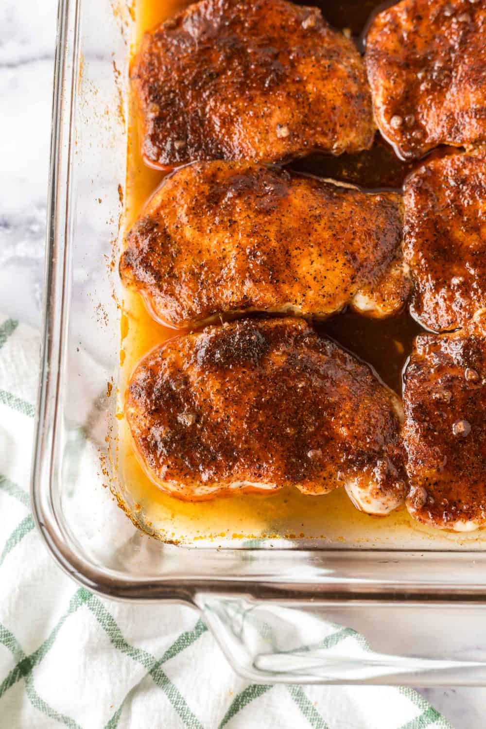 clear baking dish with seasoned pork chops in a sauce
