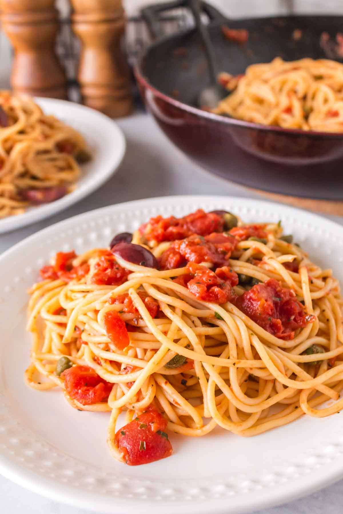 pasta puttanesca with red sauce on a white plate