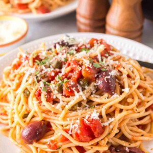 pasta puttanesca with red sauce on a white plate