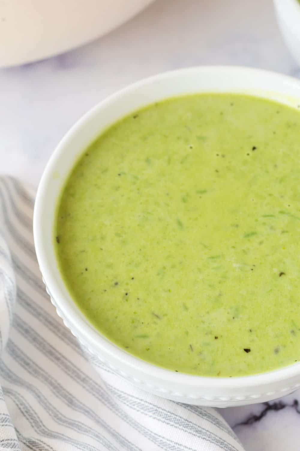 vibrant green pea soup in serving bowls and gold spoons