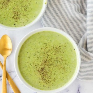 vibrant green pea soup in serving bowls with pepper on top