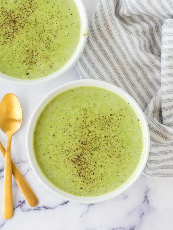 vibrant green pea soup in serving bowls with pepper on top