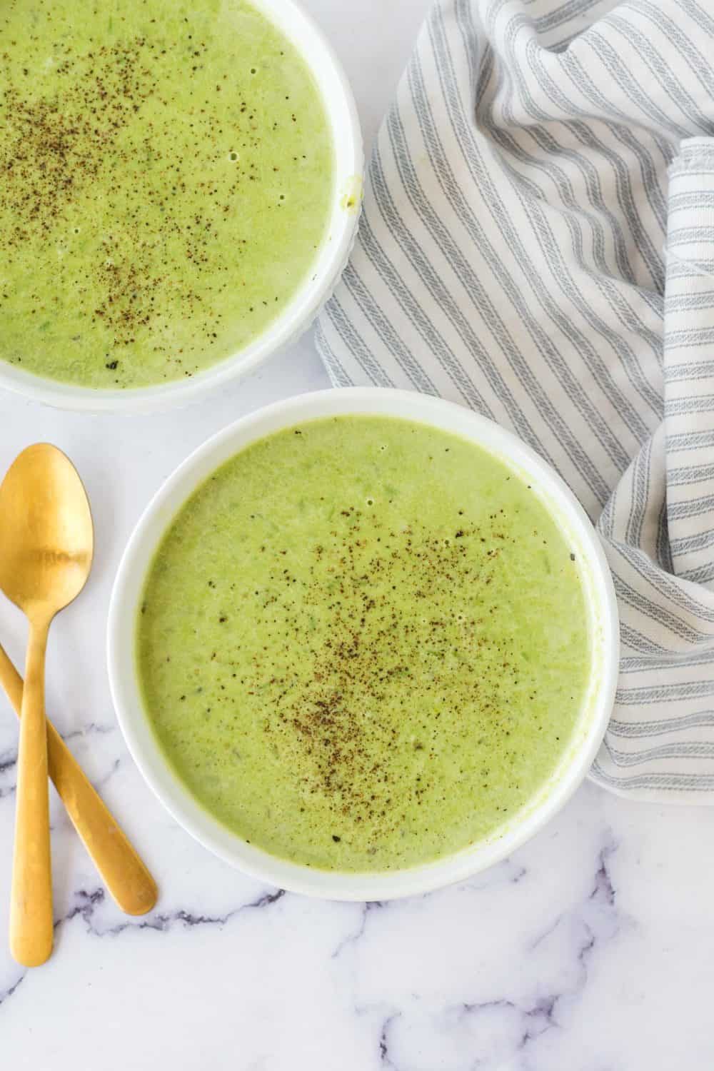 vibrant green pea soup in serving bowls with pepper on top