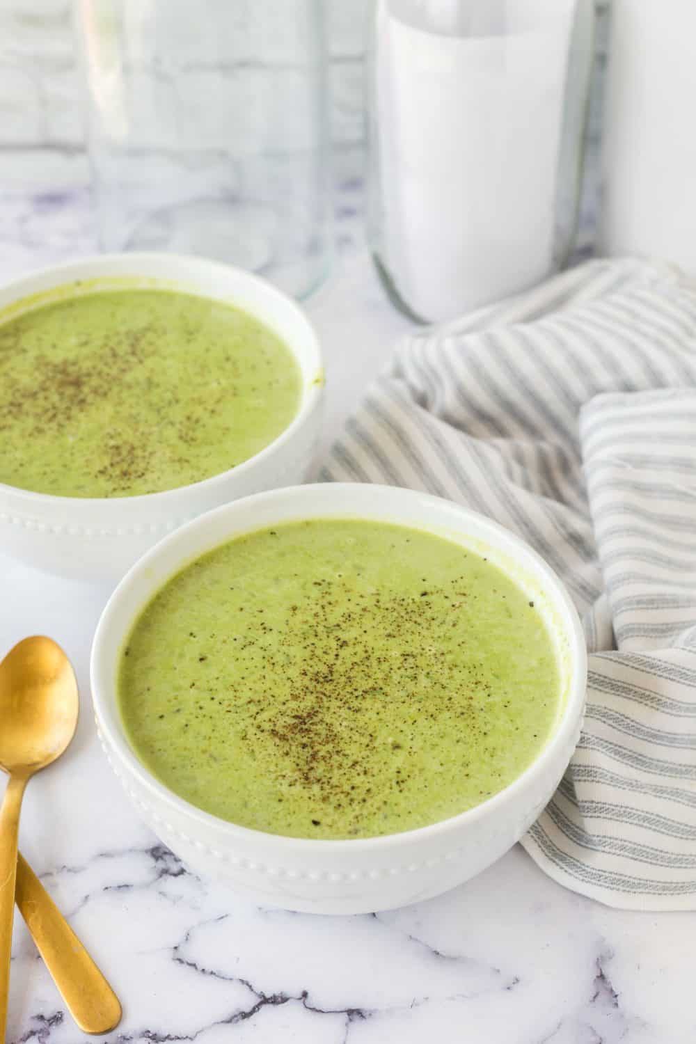 vibrant green pea soup in serving bowls with pepper on top