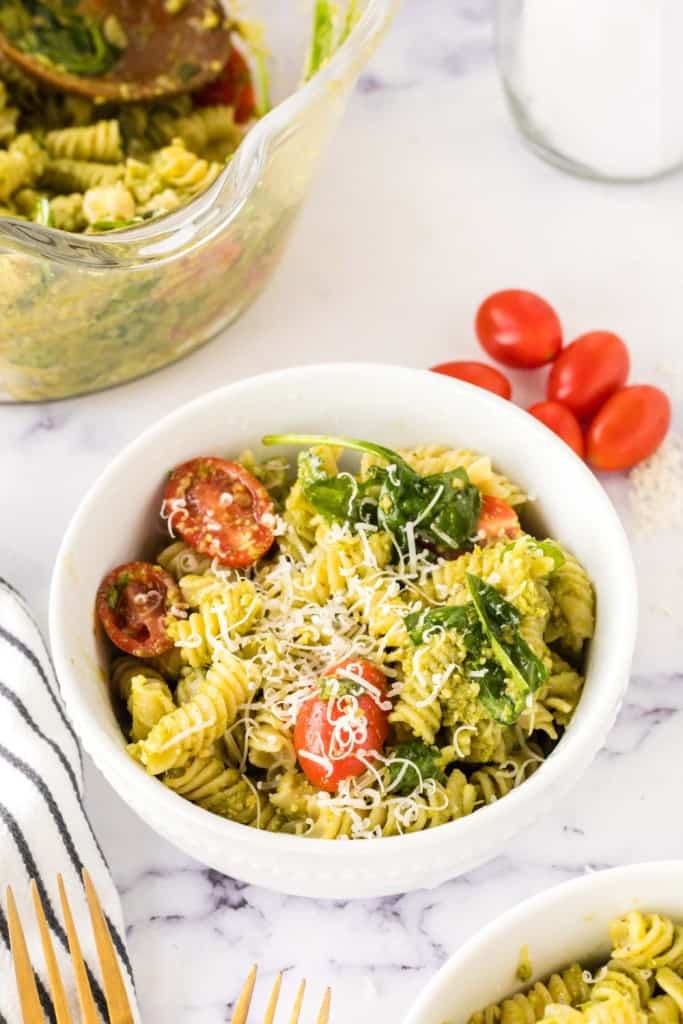portion bowl of pesto pasta salad with shredded parmesan cheese