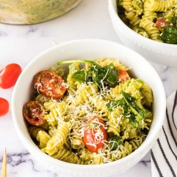 portion bowl of pesto pasta salad with shredded parmesan cheese