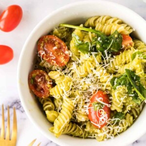 top view of a portion bowl of pesto pasta salad with shredded parmesan cheese