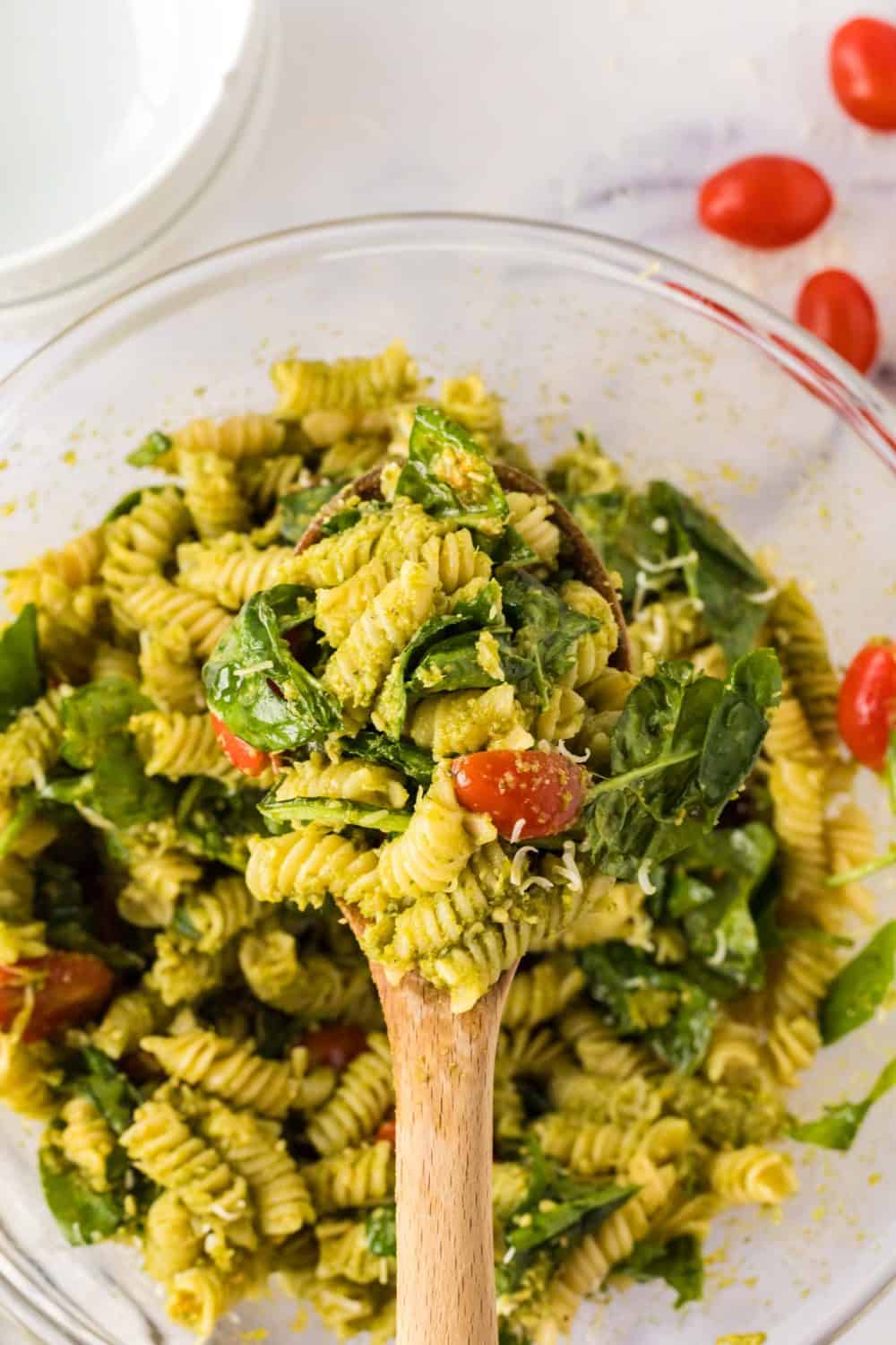 top view of a clear mixing bowl with pesto pasta salad