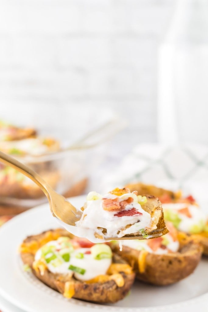 a forkful of baked potato skins with melted cheese sour cream and toppings