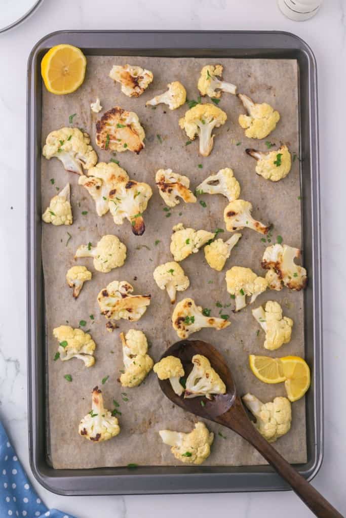 baking dish with roasted cauliflower lemon and a wooden spoon