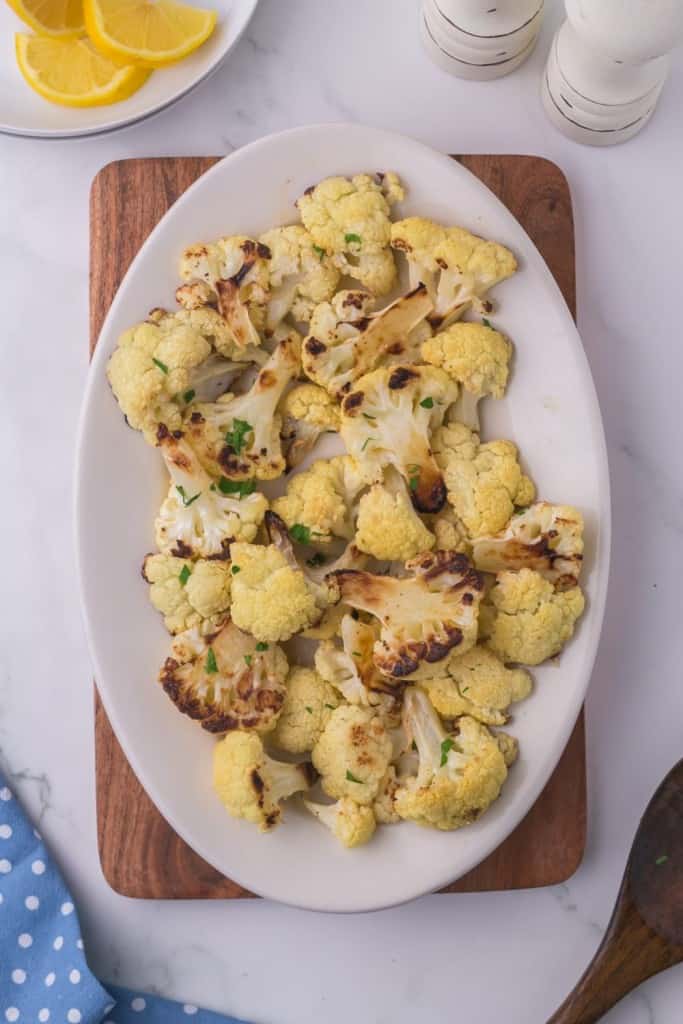 round white plate with seasoned roasted cauliflower and lemon