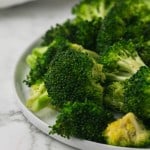 close up of view of a round white plate of sautéed broccoli