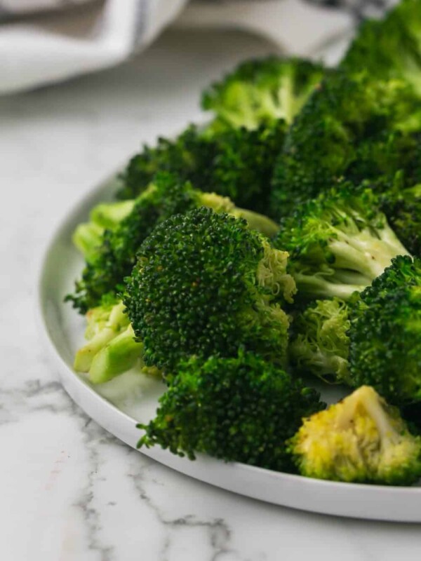 close up of view of a round white plate of sautéed broccoli