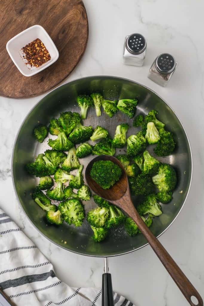sautéed pan of broccoli and a wooden spoon