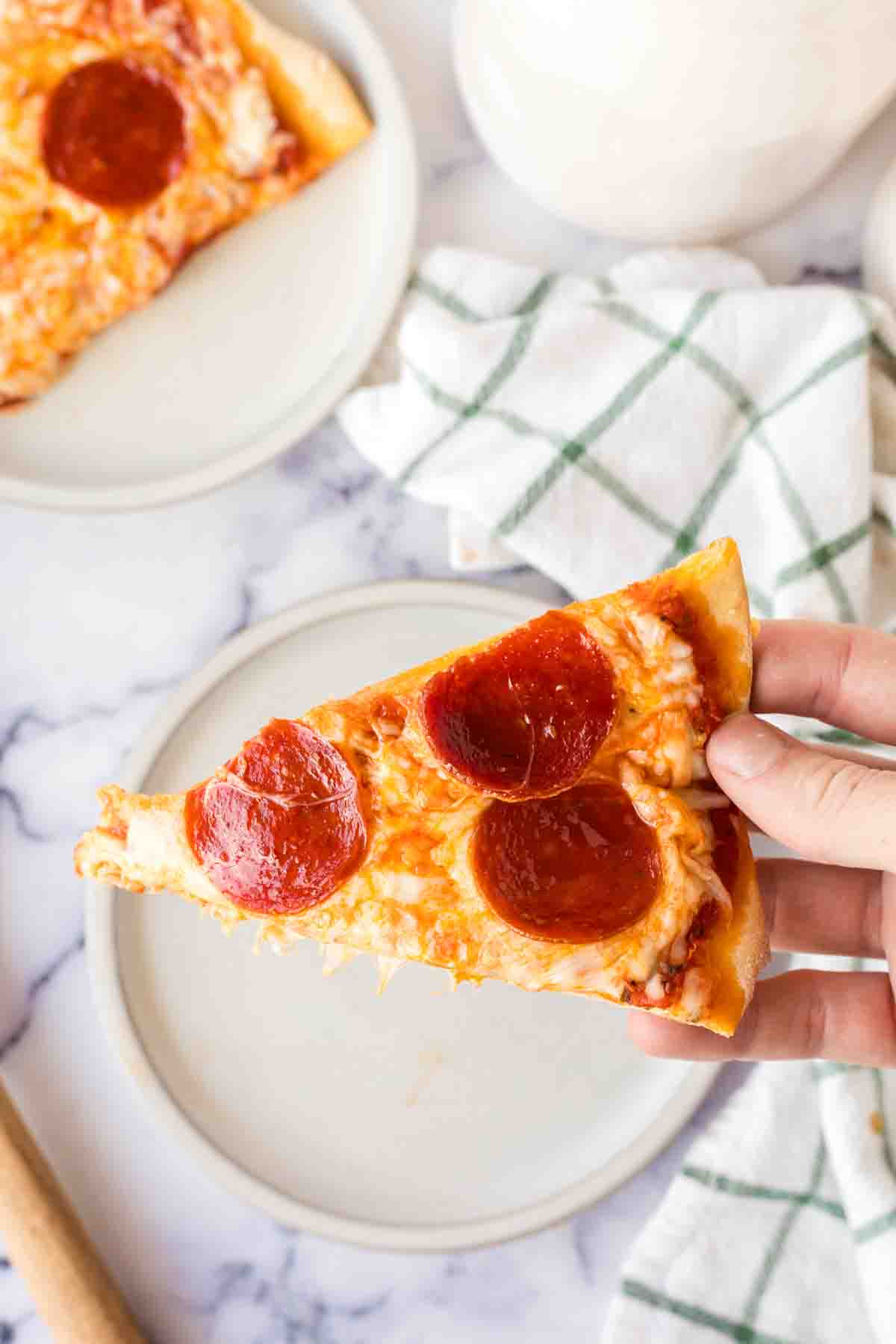 POV hand holding one slice of brooklyn style pizza