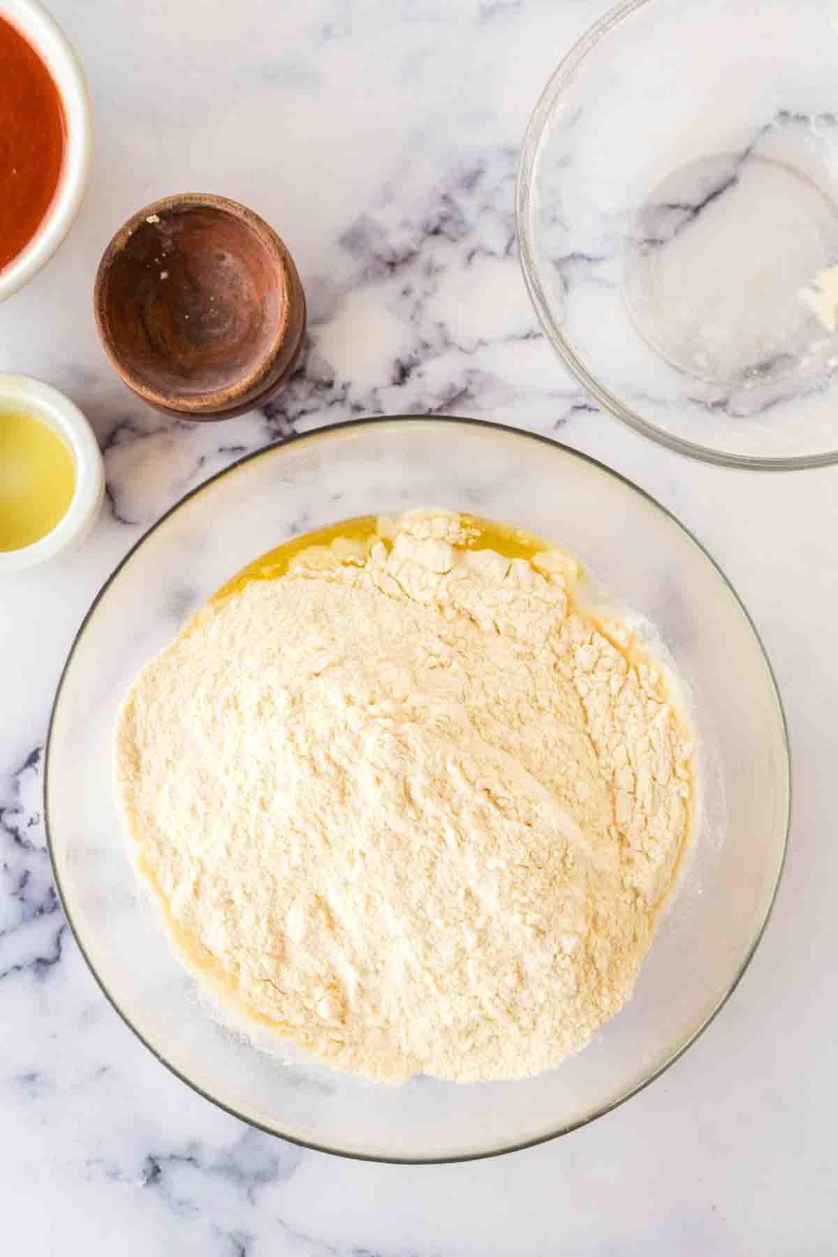 step by step of brooklyn pizza dough in the process in a clear mixing bowl