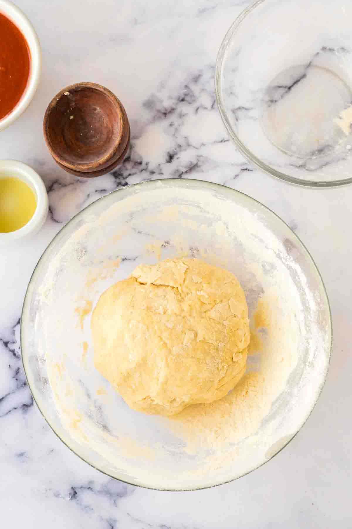 step by step of brooklyn pizza dough in the process in a clear mixing bowl