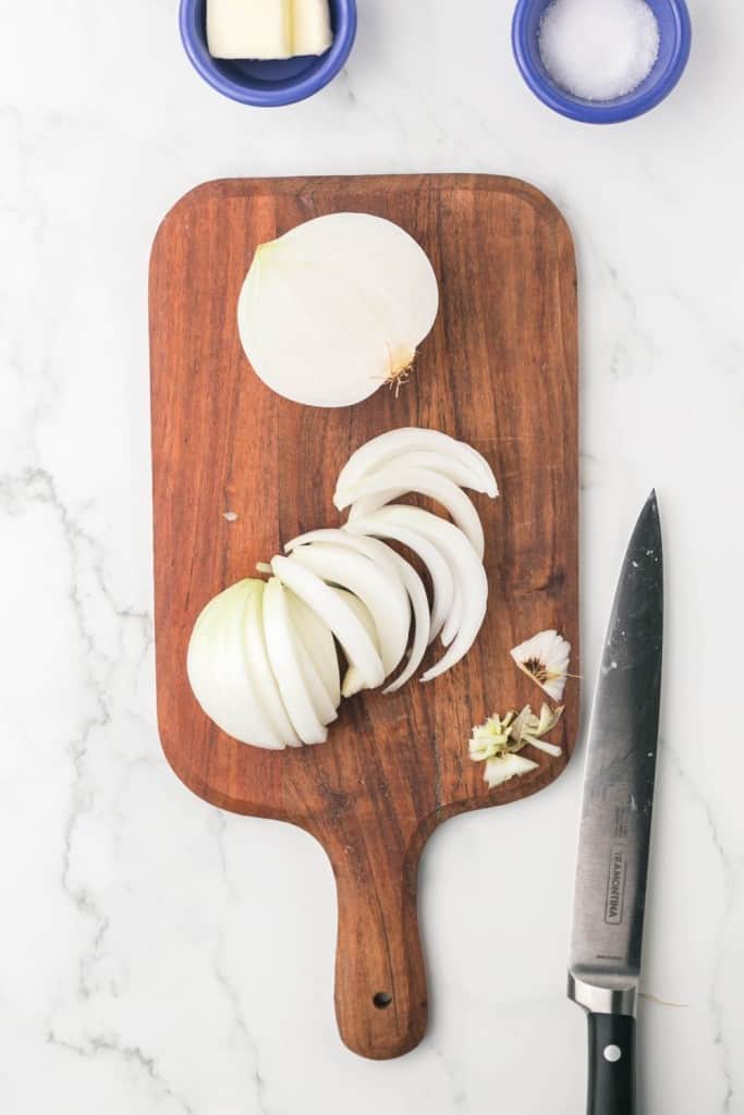 caramelized onion recipe with a raw white onion on a chopping block