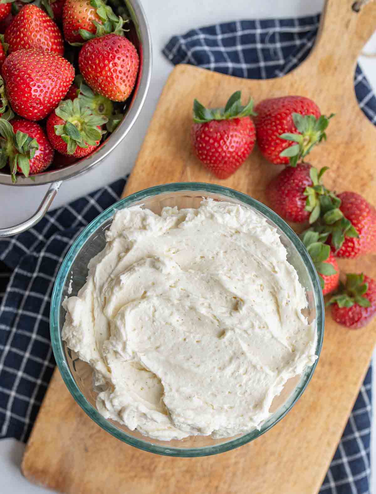 Bowl of chantilly cream with strawberries nearby.