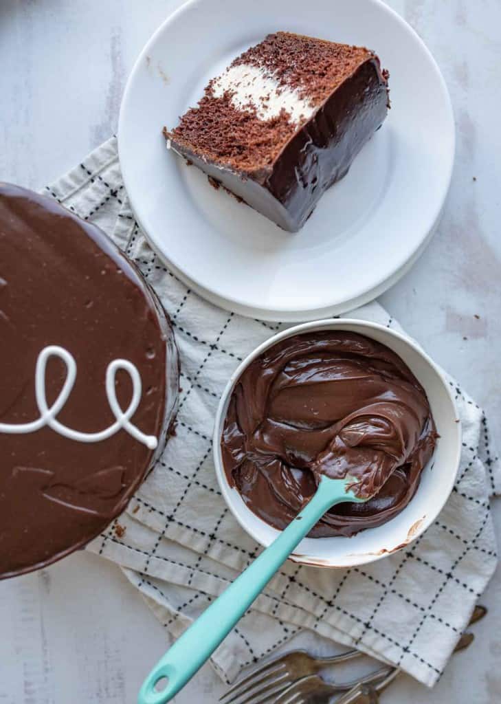 chocolate ganache whipped up in a mixing bowl next to a slice of cake