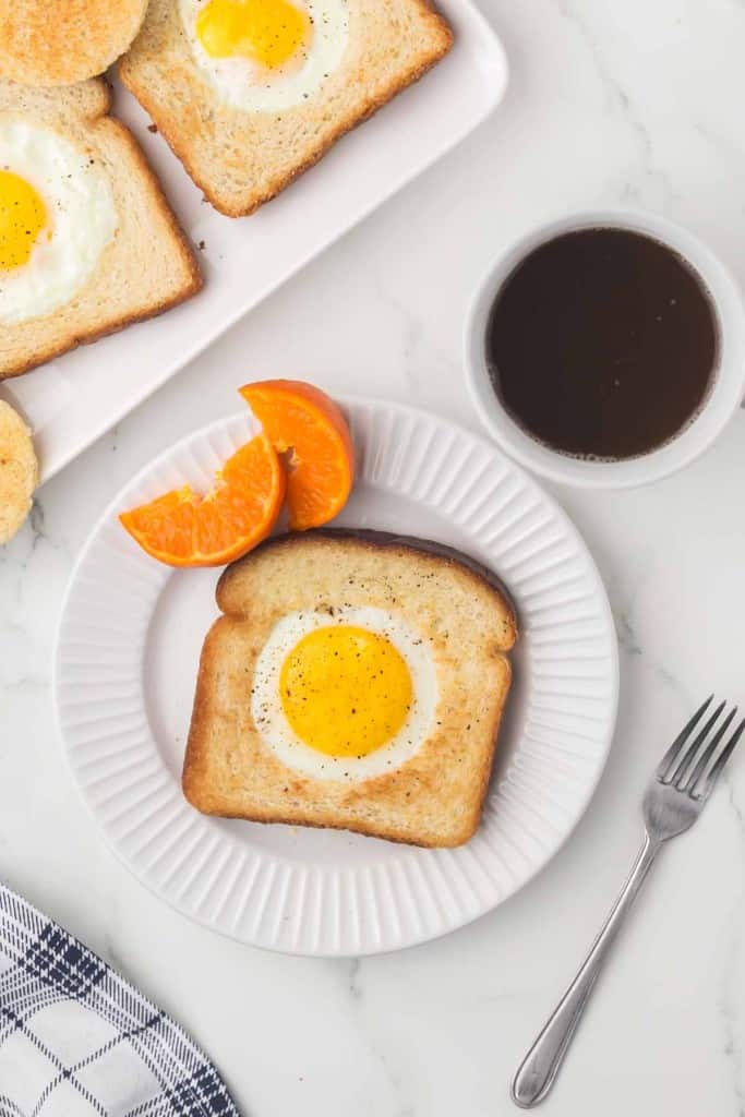 egg fried in a hole of toast with oranges and coffee