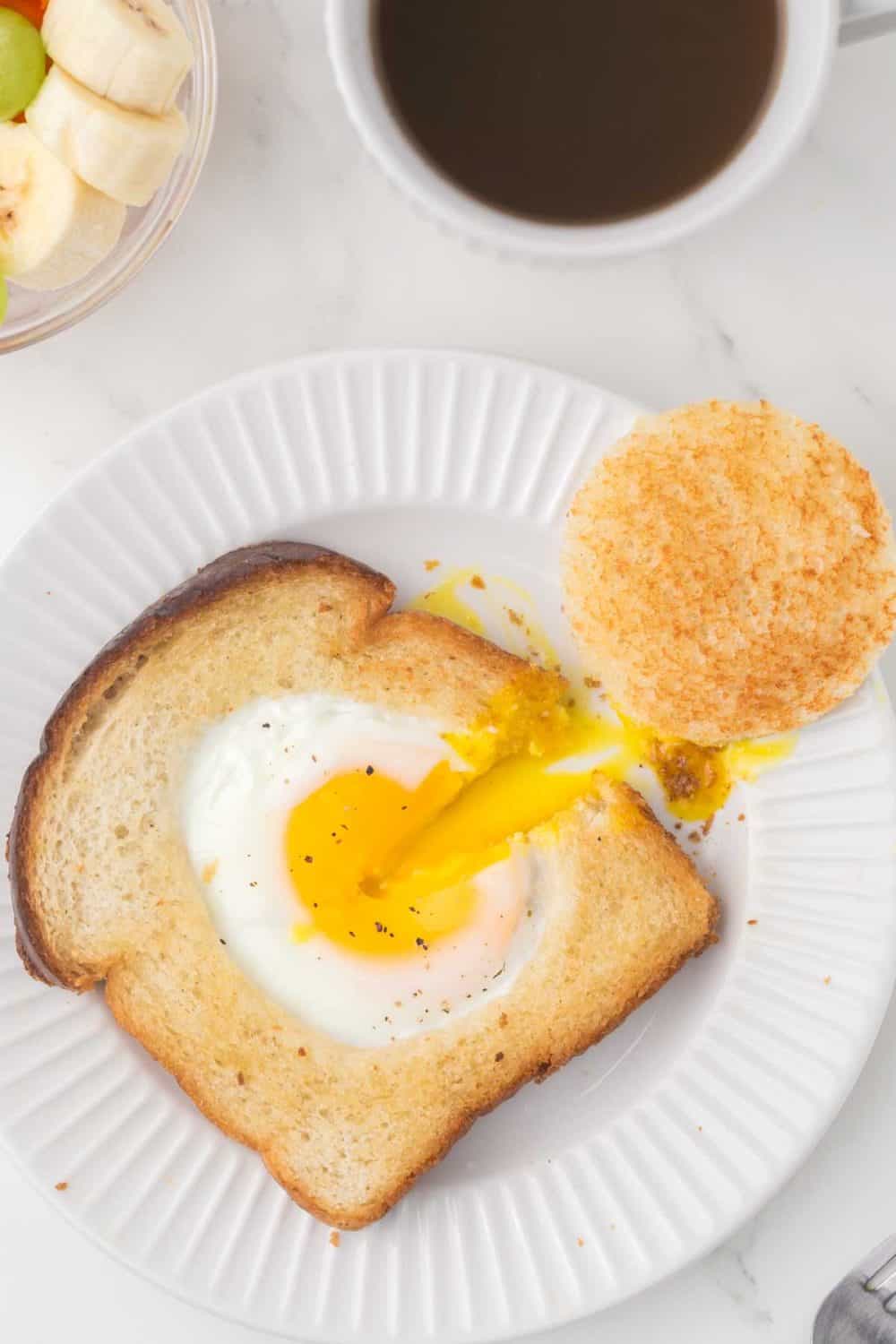 egg fried in a hole of toast with oranges and coffee