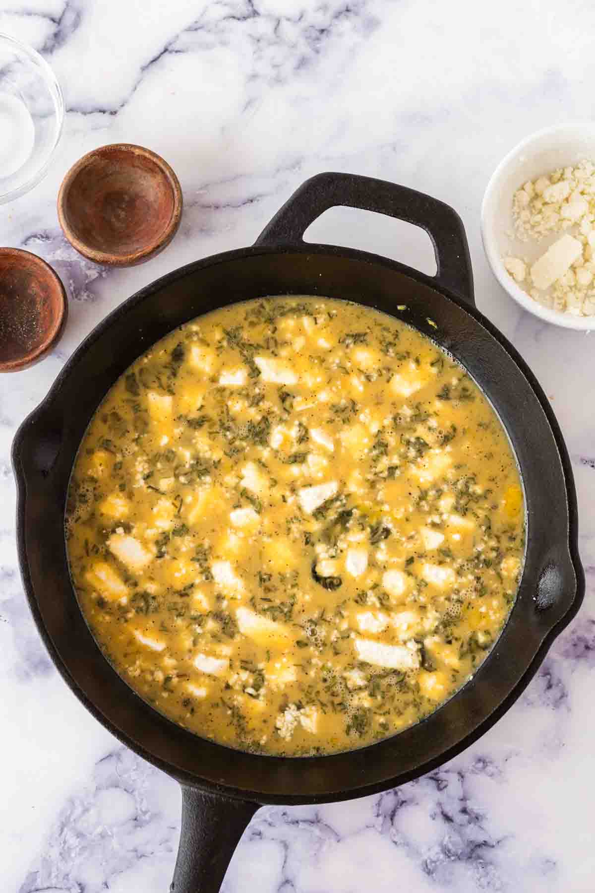 raw ingredients for the frittata recipe in a cast iron pan