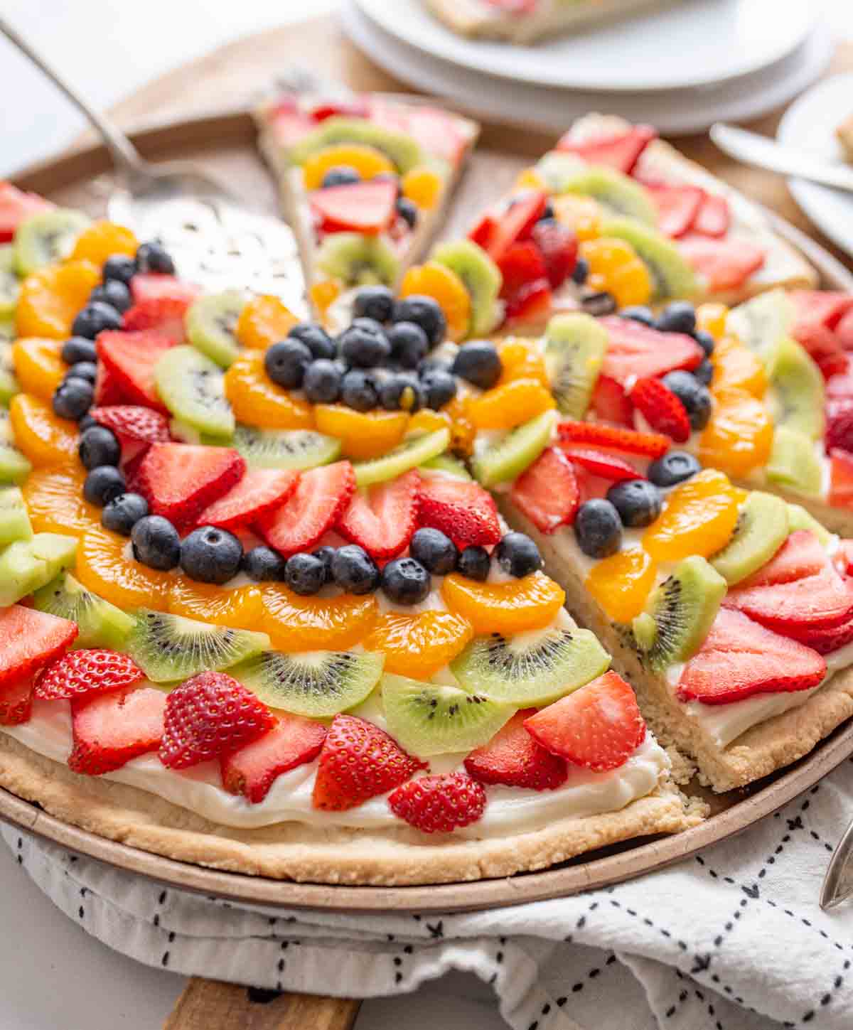 whole fruit pizza with slices of colorful fruit organized in a near mandala design on a round plate