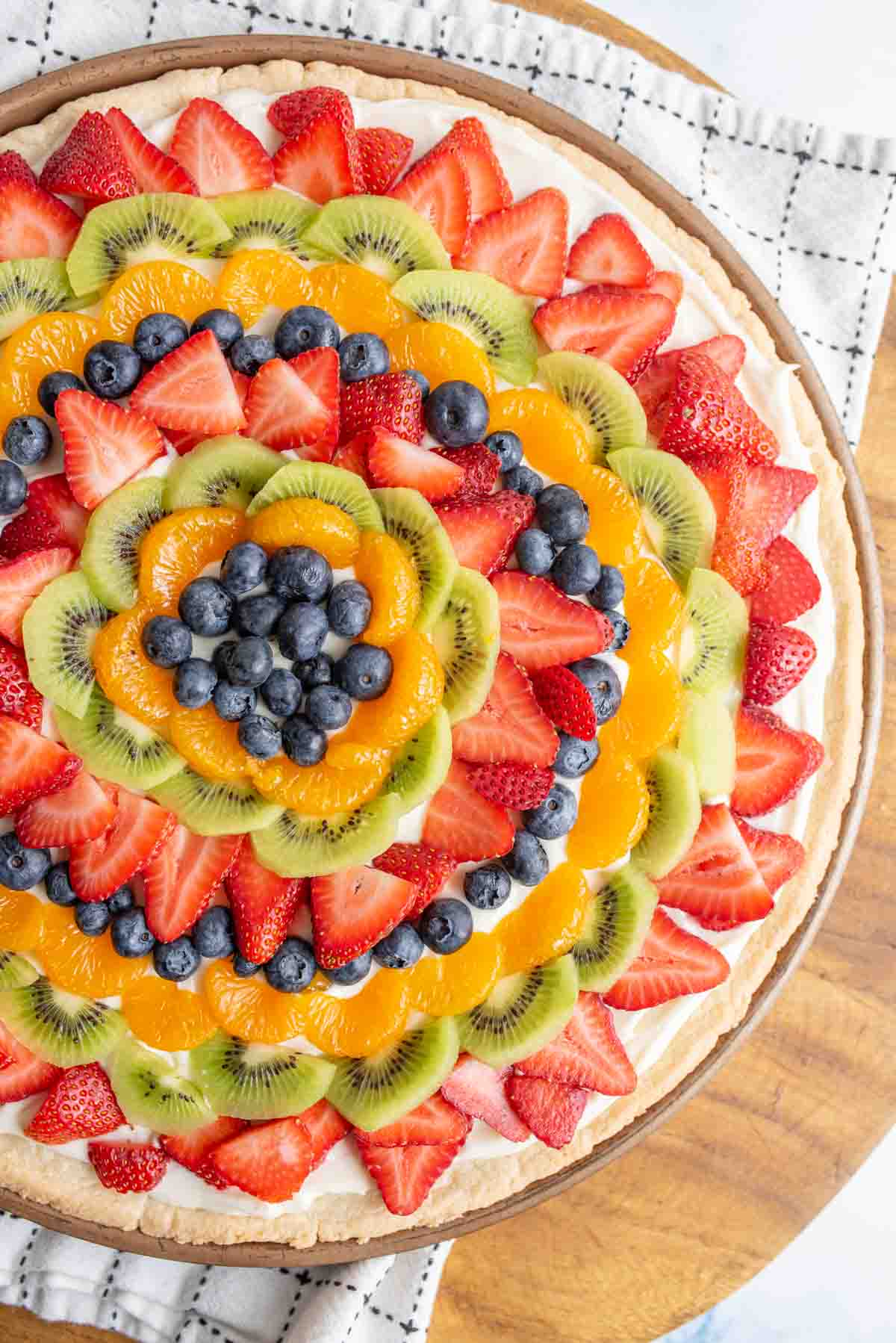 whole fruit pizza with slices of colorful fruit organized in a near mandala design on a round plate