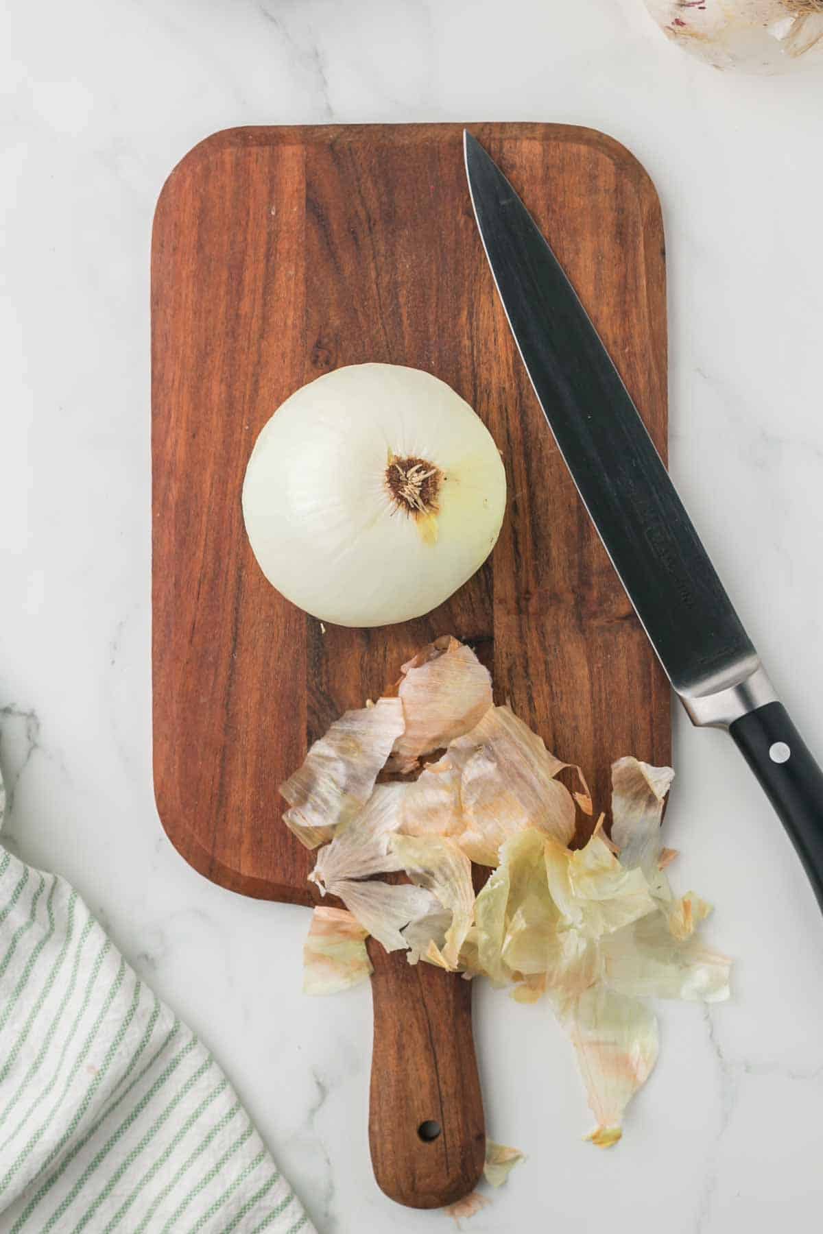 how to dice an onion, white onion on a wooden chopping block step by step