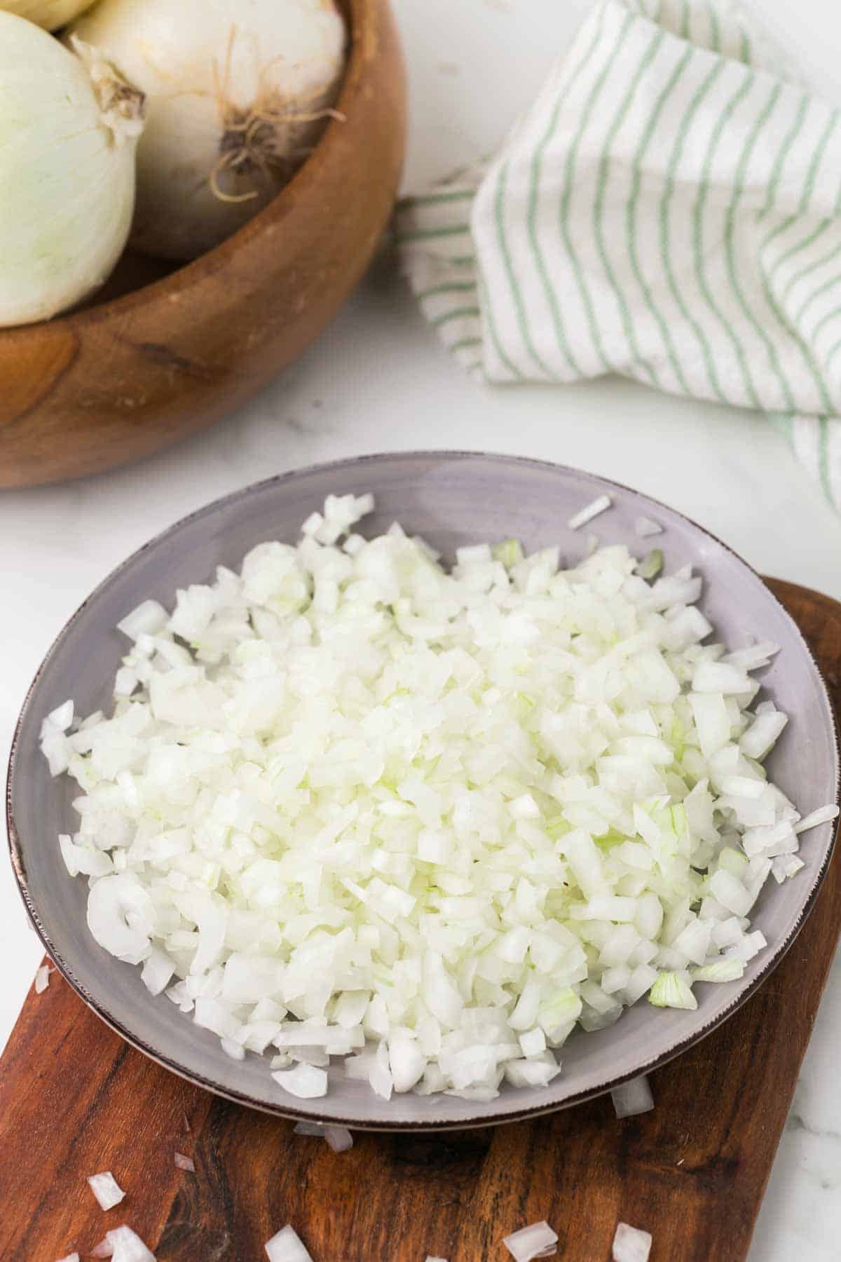 how to dice an onion: diced white onion on a clear grey dish