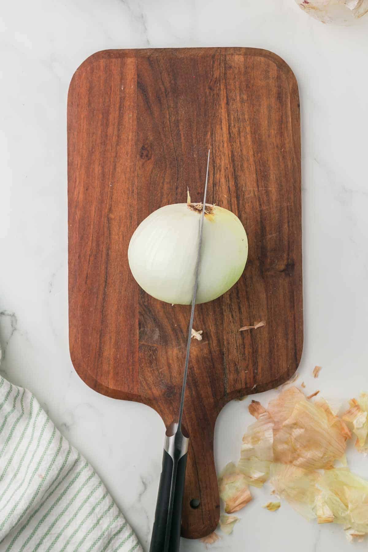 how to dice an onion, white onion on a wooden chopping block step by step