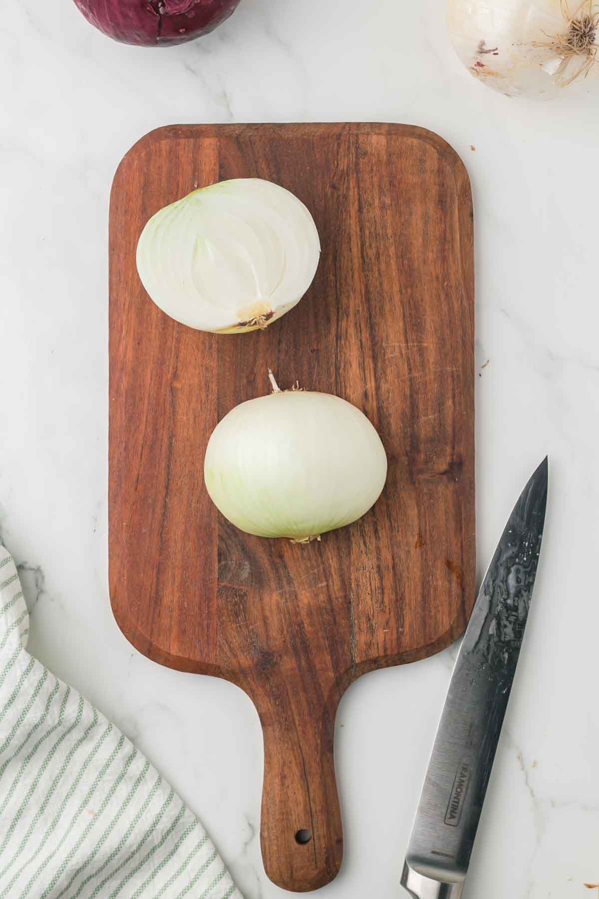 how to dice an onion, white onion on a wooden chopping block step by step
