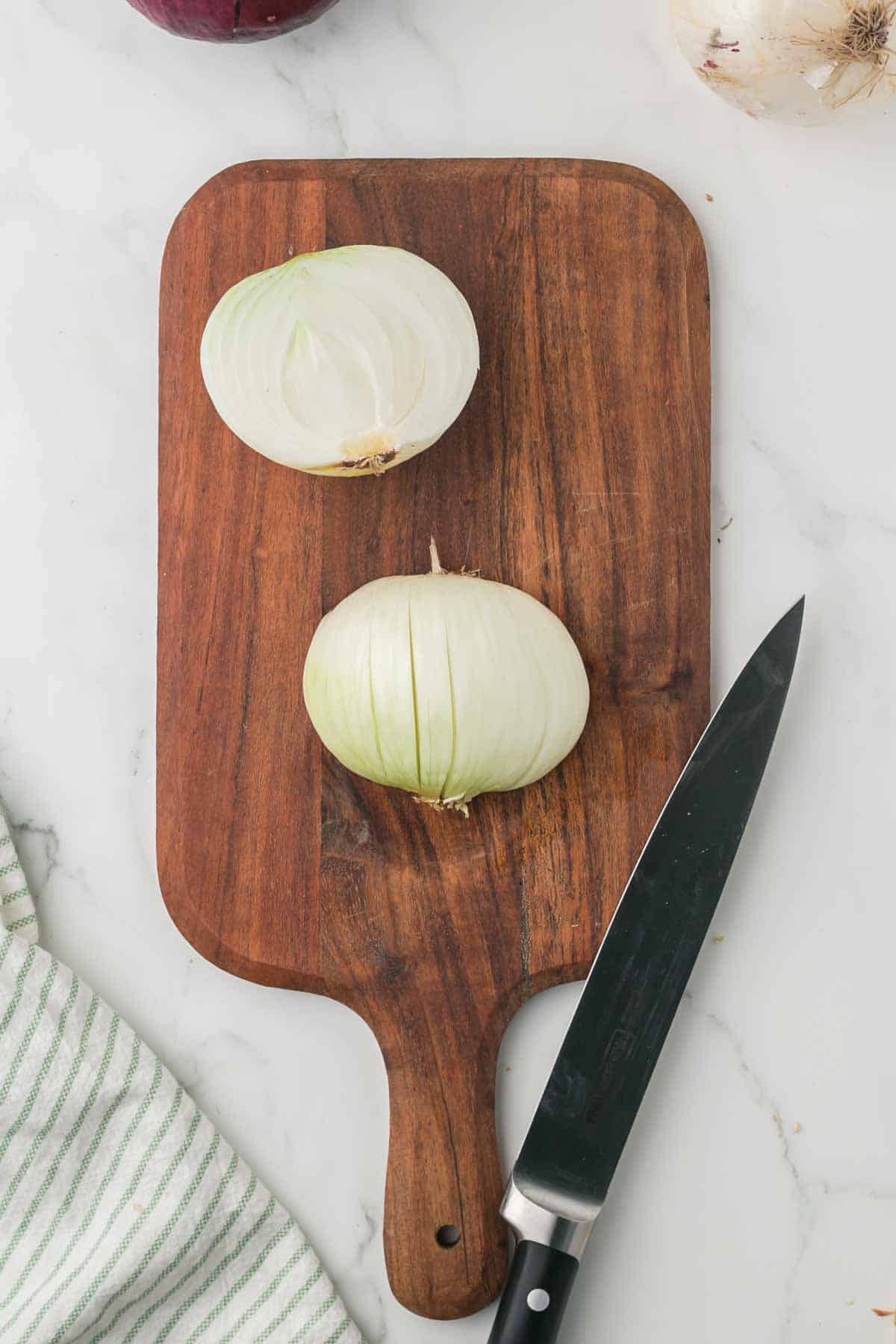 how to dice an onion, white onion on a wooden chopping block step by step