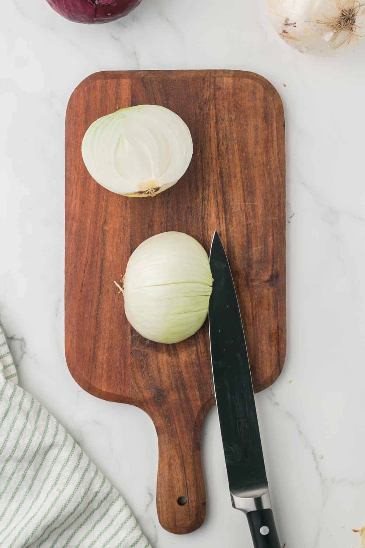 how to dice an onion, white onion on a wooden chopping block step by step