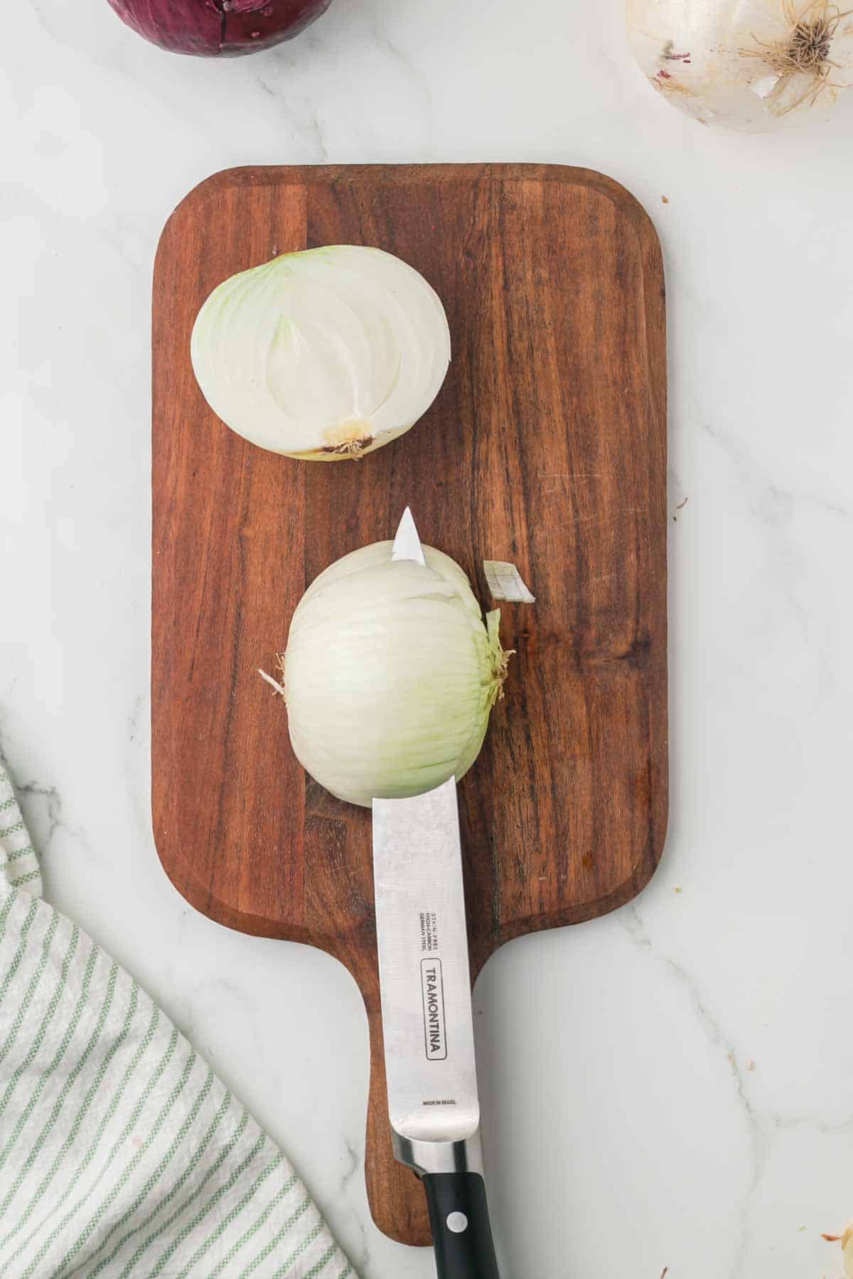 how to dice an onion, white onion on a wooden chopping block step by step