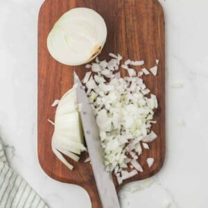 how to dice an onion, white onion on a wooden chopping block step by step