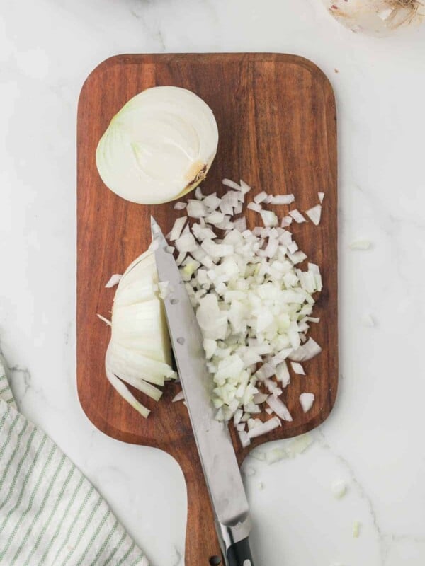 how to dice an onion, white onion on a wooden chopping block step by step